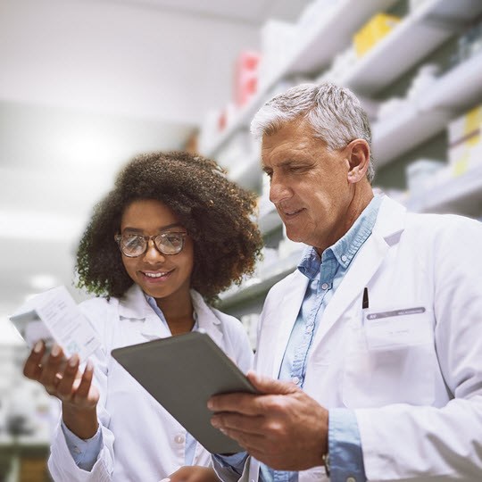 Two focused pharmacist walking around and doing stock inside of a pharmacy